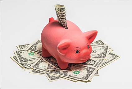 pink piggy bank with dollar sticking out of top.