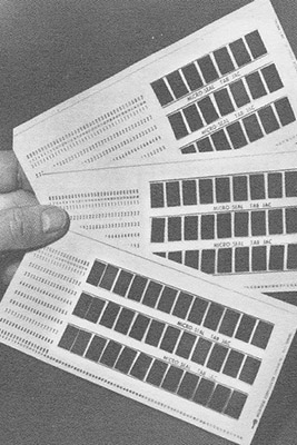 Hand holding aperture cards with 36 slots for microfilm.
