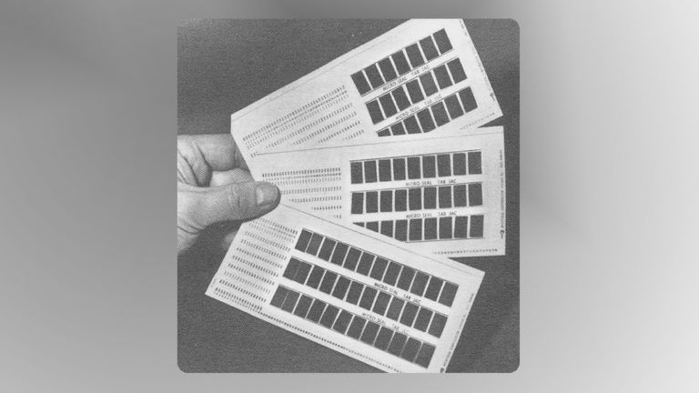 black and white photo of a hand holding microfilm multiple aperture cards.